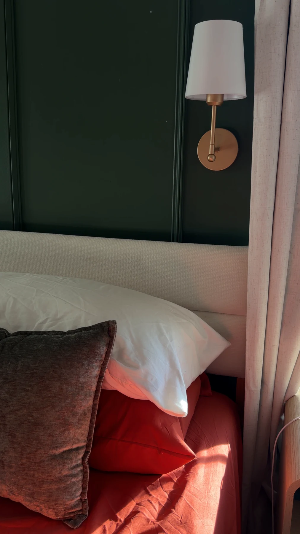 A glimpse of a cozy bedroom corner with warm bedding and a green wall.